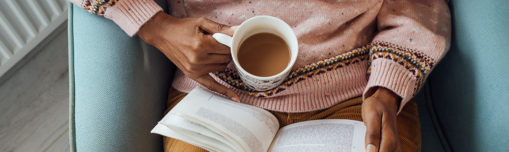 Woman reading a book and holding a cup of coffee